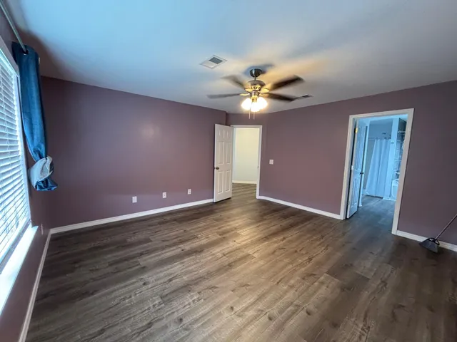 a view of an empty room with window and wooden floor