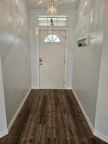a view of a hallway with wooden floor and a chandelier