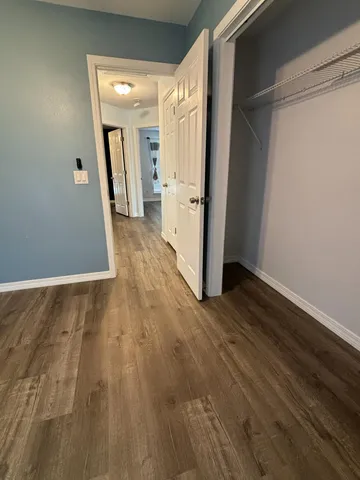 a view of a hallway with wooden floor and a bathroom