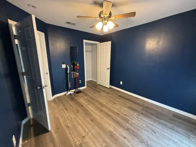 en empty room with wooden floor and fan