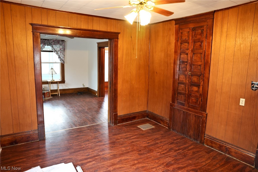 1309 Krumroy Road Akron, OH 44306 - Photo 9 of 30 Unfurnished room with wooden walls, dark wood-type flooring, and ceiling fan