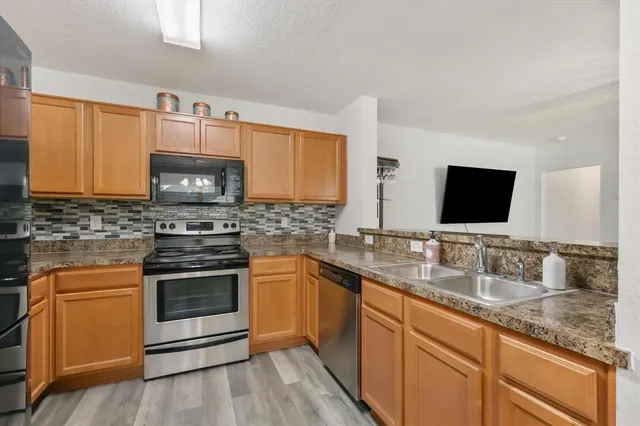 a kitchen with stainless steel appliances granite countertop a sink stove and microwave