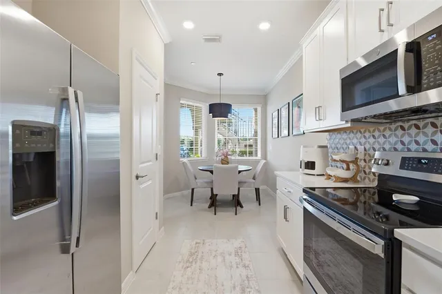 a kitchen with stainless steel appliances granite countertop a stove top oven a sink dishwasher a refrigerator and a dining table with wooden floor