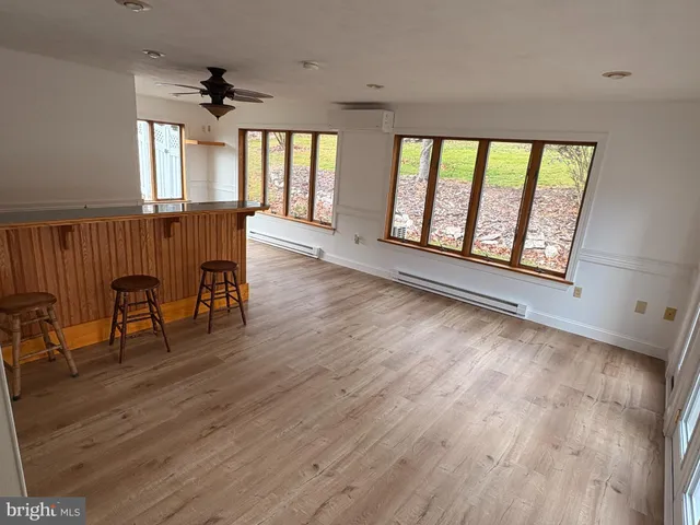 an empty room with wooden floor fan and windows