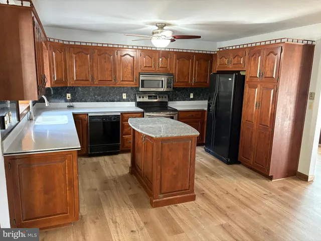 a kitchen with stainless steel appliances granite countertop a refrigerator a sink dishwasher a stove with wooden cabinets and floor