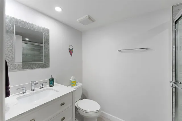 a bathroom with a granite countertop sink a toilet and a mirror