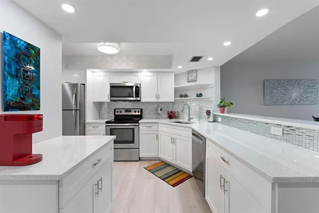 a kitchen with a sink stainless steel appliances and white cabinets