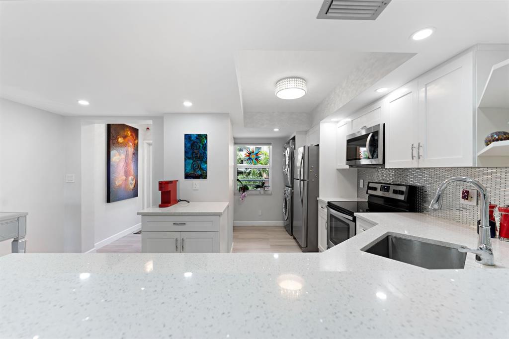 615 North Riverside Drive, Unit 502 Pompano Beach, FL 33062 - Photo 5 of 43 a kitchen with stainless steel appliances a microwave a sink a stove a refrigerator cabinets and living room view