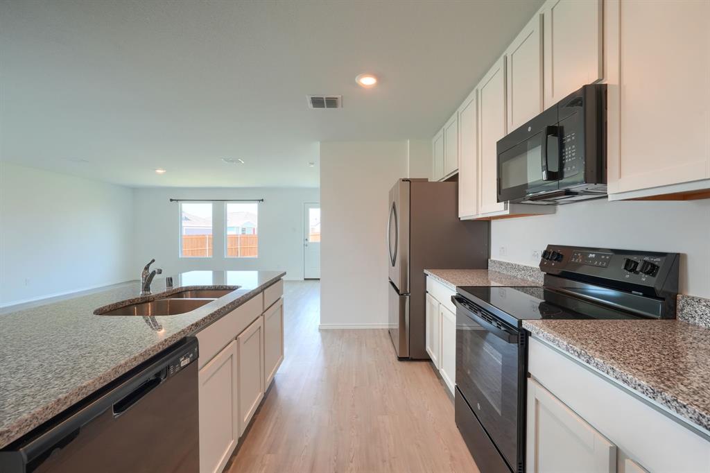5916 Crystal Water Way Princeton, TX 75407 - Photo 6 of 28 a kitchen with stainless steel appliances granite countertop a sink stove and refrigerator