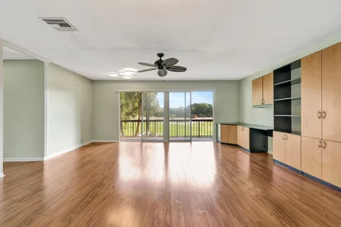 a view of empty room with wooden floor and ceiling fan