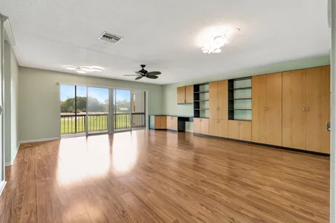 a view of an empty room with wooden floor and a ceiling fan