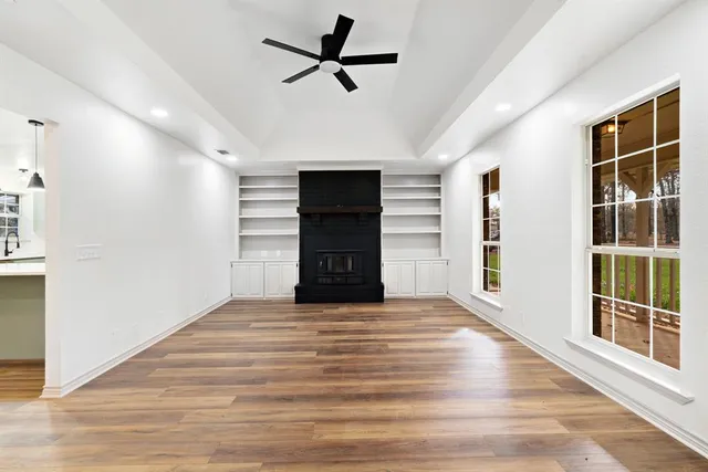 a view of an empty room with a window and a kitchen