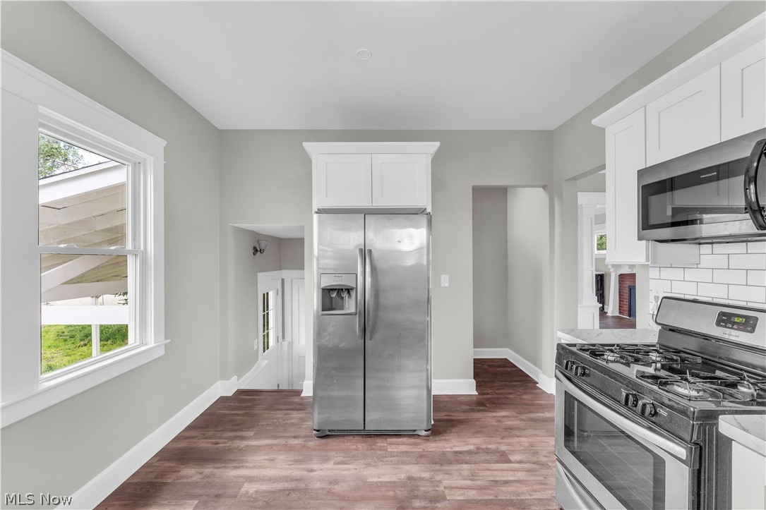 3506 Riverside Avenue Cleveland, OH 44109 - Photo 13 of 31 Kitchen featuring wood-finish flooring, stainless steel appliances, white subway tile backsplash, white cabinetry, and light gray wall paint