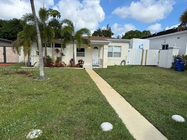 a view of a white house with a yard and potted plants