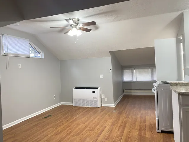 a view of empty room with wooden floor and fan