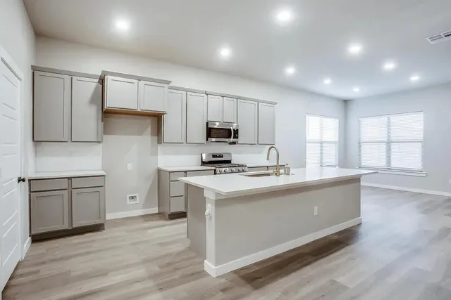 a kitchen with stainless steel appliances granite countertop a sink stove microwave and refrigerator