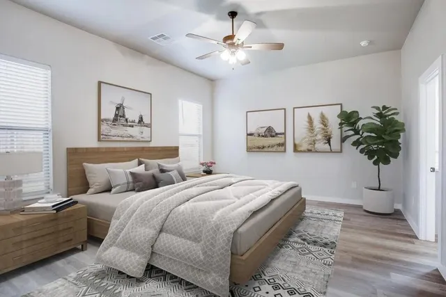an empty room with wooden floor chandelier fan and windows