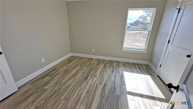 an empty room with wooden floor and windows