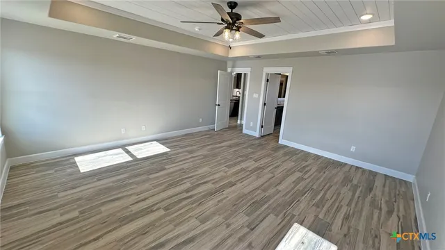 a view of empty room with wooden floor and ceiling fan