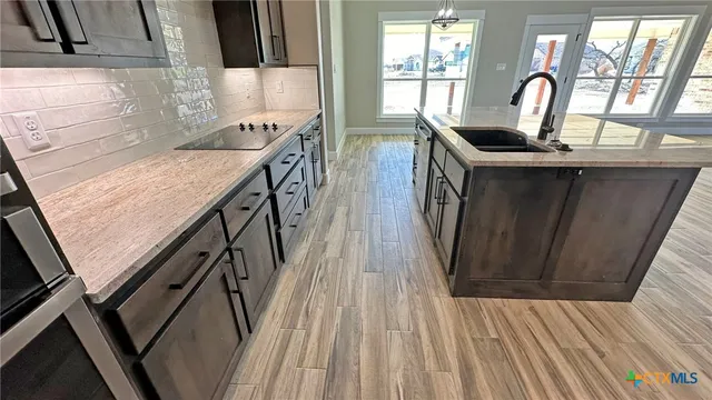 a kitchen with sink a window and wooden floor