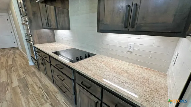 a kitchen with granite countertop a sink a stove and wooden cabinets
