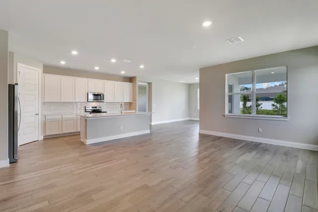 a large kitchen with stainless steel appliances a large counter top a stove and a refrigerator