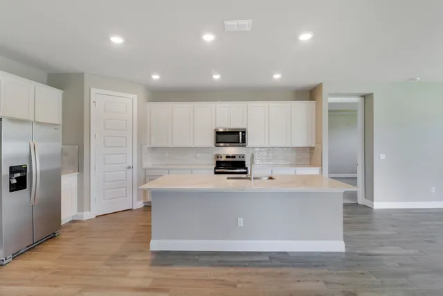 a large kitchen with stainless steel appliances granite countertop a large counter top a sink and a stove