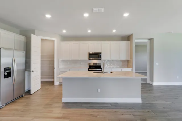 a kitchen with granite countertop a refrigerator and a stove top oven