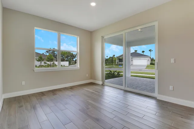 an empty room with wooden floor and windows