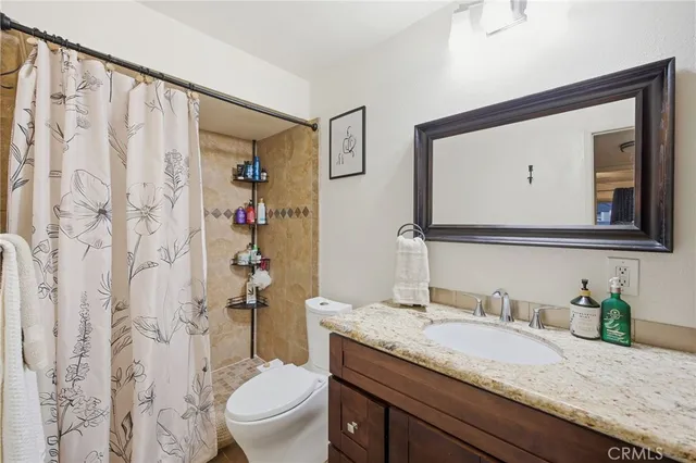 a bathroom with a granite countertop sink and a mirror with toilet