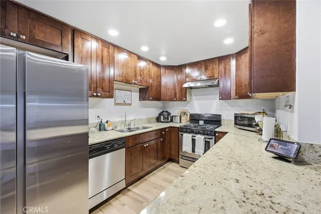 a kitchen with kitchen island granite countertop a sink stainless steel appliances and cabinets