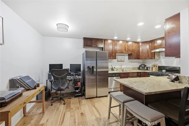 a kitchen with a refrigerator a stove a sink and a dining table with wooden floor