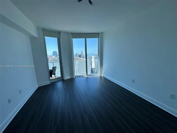 a view of an empty room with wooden floor and windows
