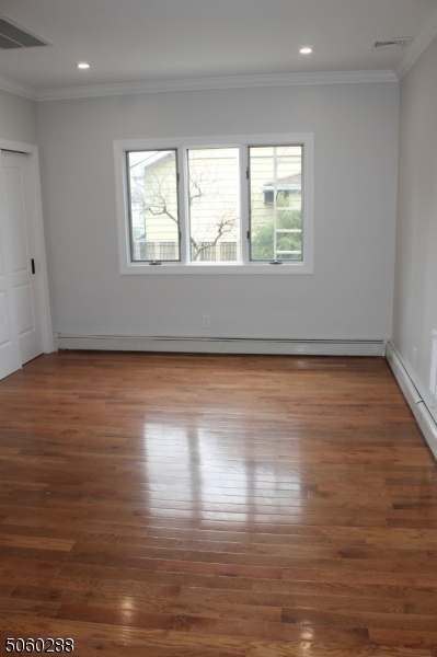 164 Main Street, Unit 2 Garfield, NJ 07026 - Photo 5 of 24 an empty room with wooden floor and windows