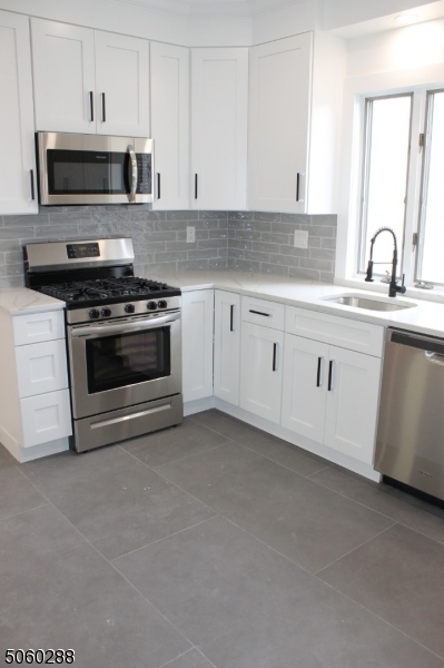164 Main Street, Unit 2 Garfield, NJ 07026 - Photo 9 of 24 a kitchen with stainless steel appliances granite countertop a stove a sink and a microwave
