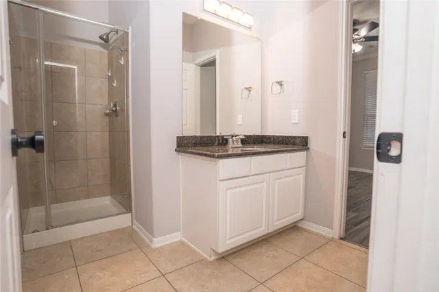 a bathroom with a granite countertop sink a mirror and shower