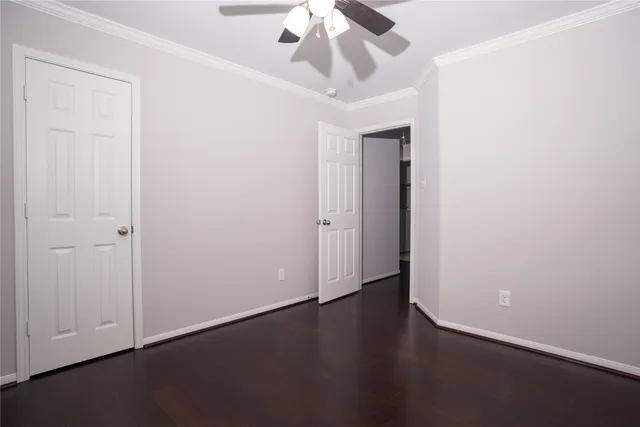 an empty room with wooden floor closet and windows