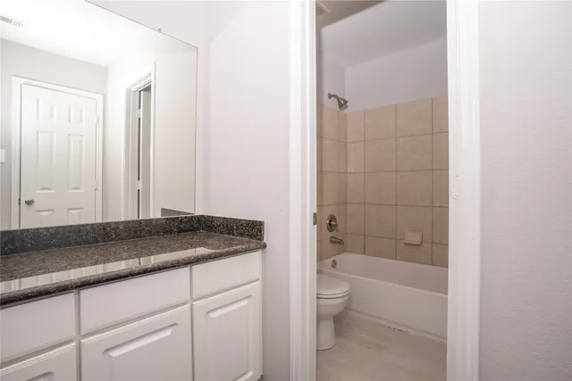 a bathroom with a granite countertop sink a toilet and bathtub