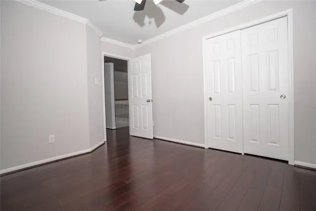 an empty room with wooden floor chandelier fan and windows