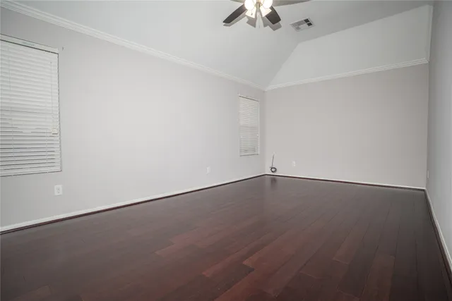 an empty room with a chandelier fan and wooden floor