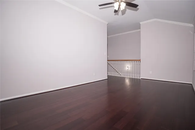 an empty room with wooden floor chandelier fan and windows