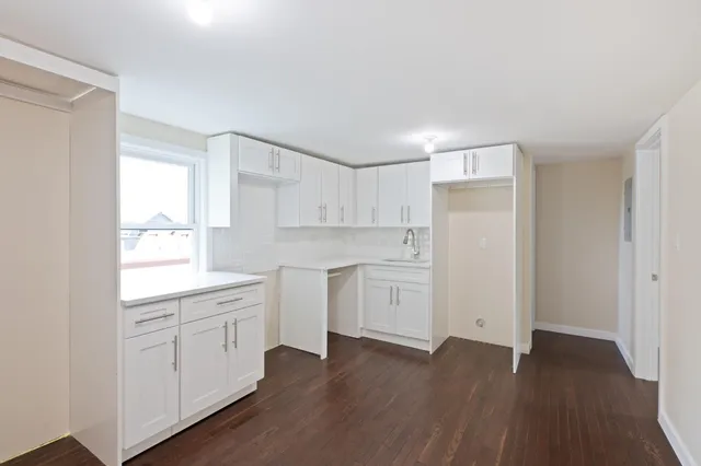 a kitchen with white cabinets and sink