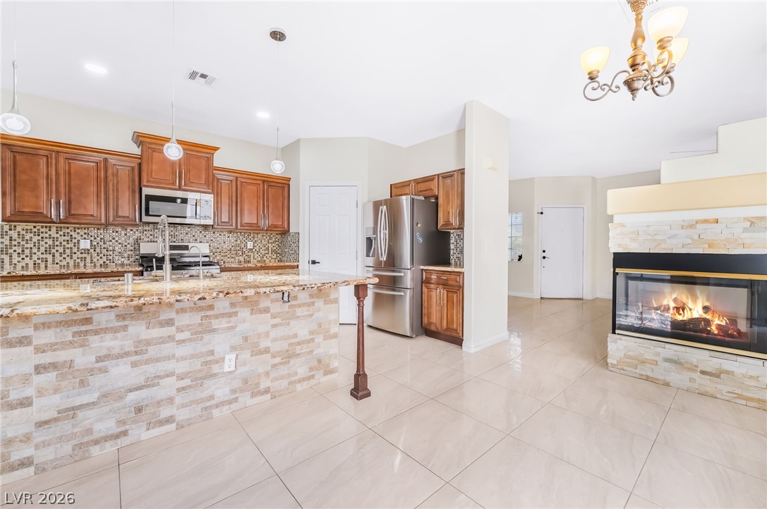 5905 Crumbling Ridge Street Henderson, NV 89011 - Photo 8 of 28 Polished tile flooring anchors the open kitchen and living area complete with a stone-faced fireplace.