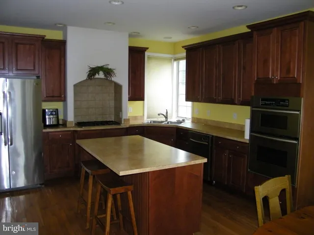 a kitchen with kitchen island granite countertop wooden cabinets a refrigerator and a stove