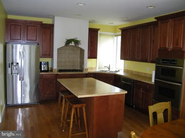 a kitchen with kitchen island granite countertop wooden cabinets a refrigerator and a stove