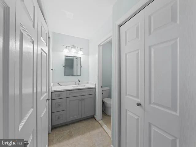 a bathroom with a granite countertop toilet sink mirror and vanity