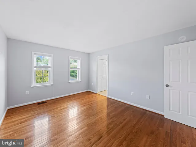 a bedroom with wooden floor and window