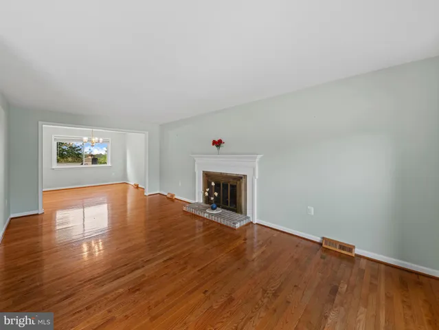 a view of an empty room with wooden floor and a fireplace