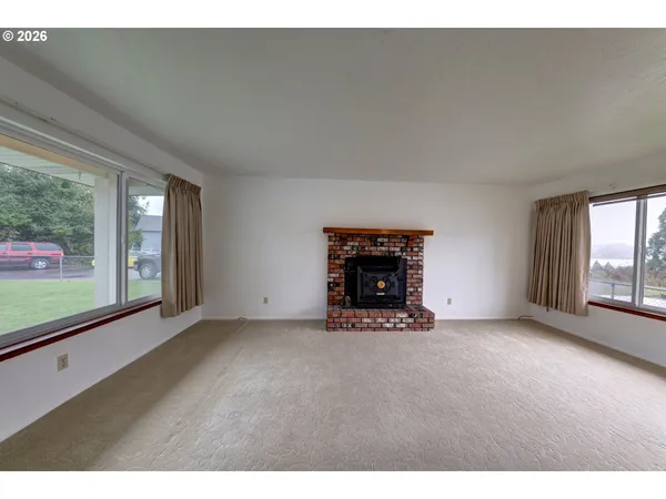 a view of an empty room with a fireplace and a window