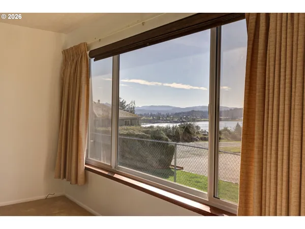 a view of a room with a large window and wooden floor
